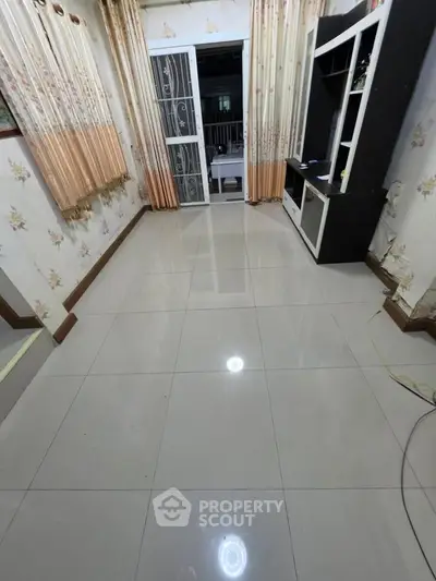 Spacious living room with tiled flooring and open balcony access, ideal for modern living.