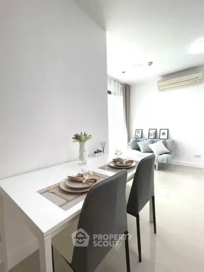 Modern dining area with sleek table and chairs, adjacent to cozy living space with natural light.