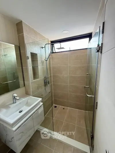 Modern bathroom with glass shower and sleek sink in contemporary apartment.