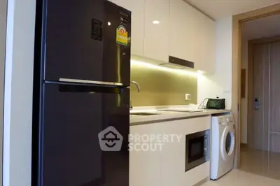 Modern kitchen with sleek appliances including fridge, washing machine, and microwave in stylish apartment.