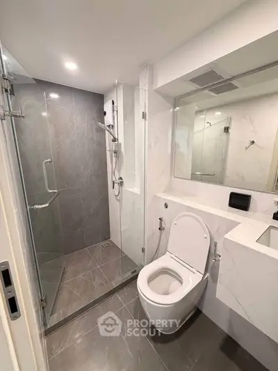 Modern bathroom with glass shower and sleek fixtures in luxury apartment.