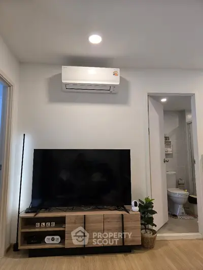 Modern living room with air conditioning and TV, adjacent to a bathroom, showcasing sleek design and functionality.