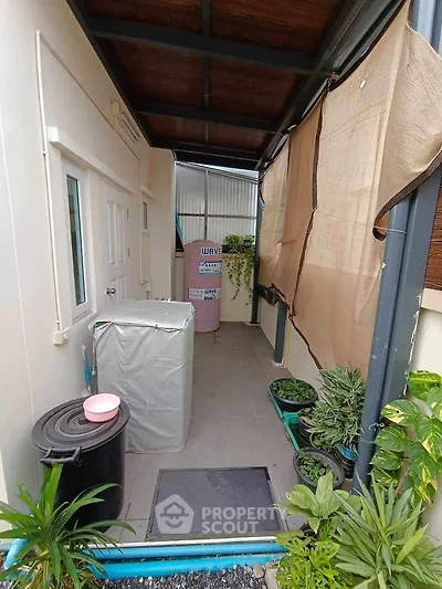 Charming outdoor utility area with plants and covered appliances