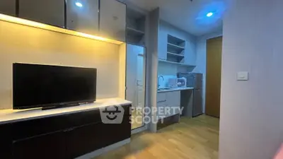 Modern living area with sleek TV setup and compact kitchen