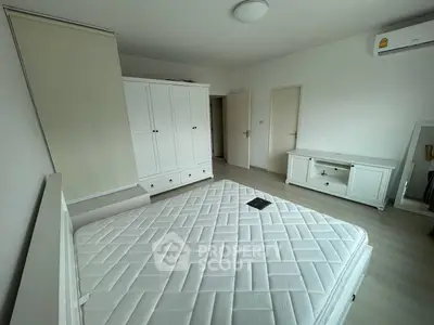 Spacious bedroom with modern white furniture and ample natural light, perfect for a serene living experience.
