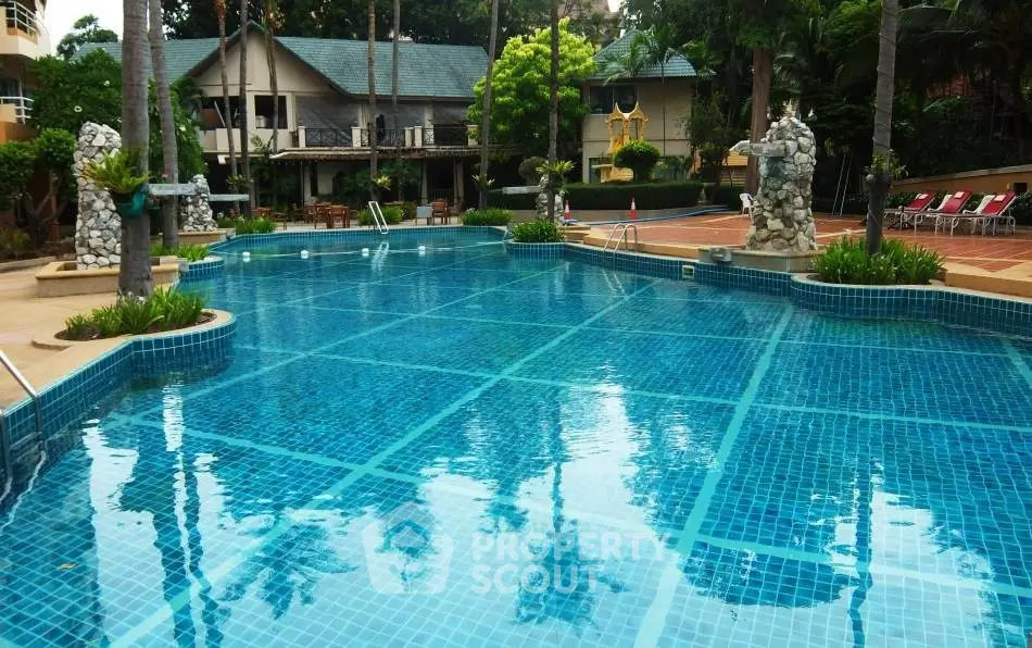 Luxurious outdoor pool area with lush greenery and elegant stone sculptures, perfect for relaxation.