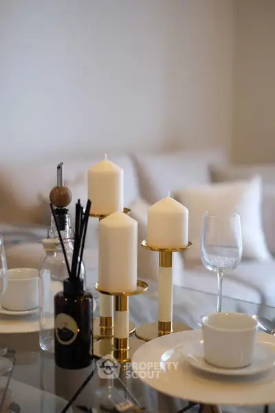 Elegant dining table setup with candles and glassware in a modern living room.