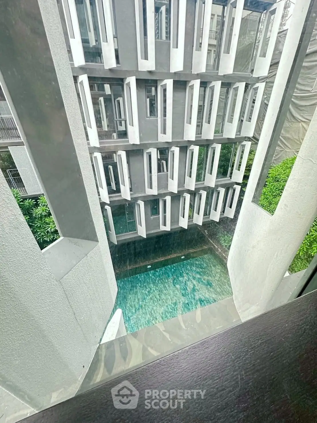 Modern building with unique window design overlooking a serene pool area.