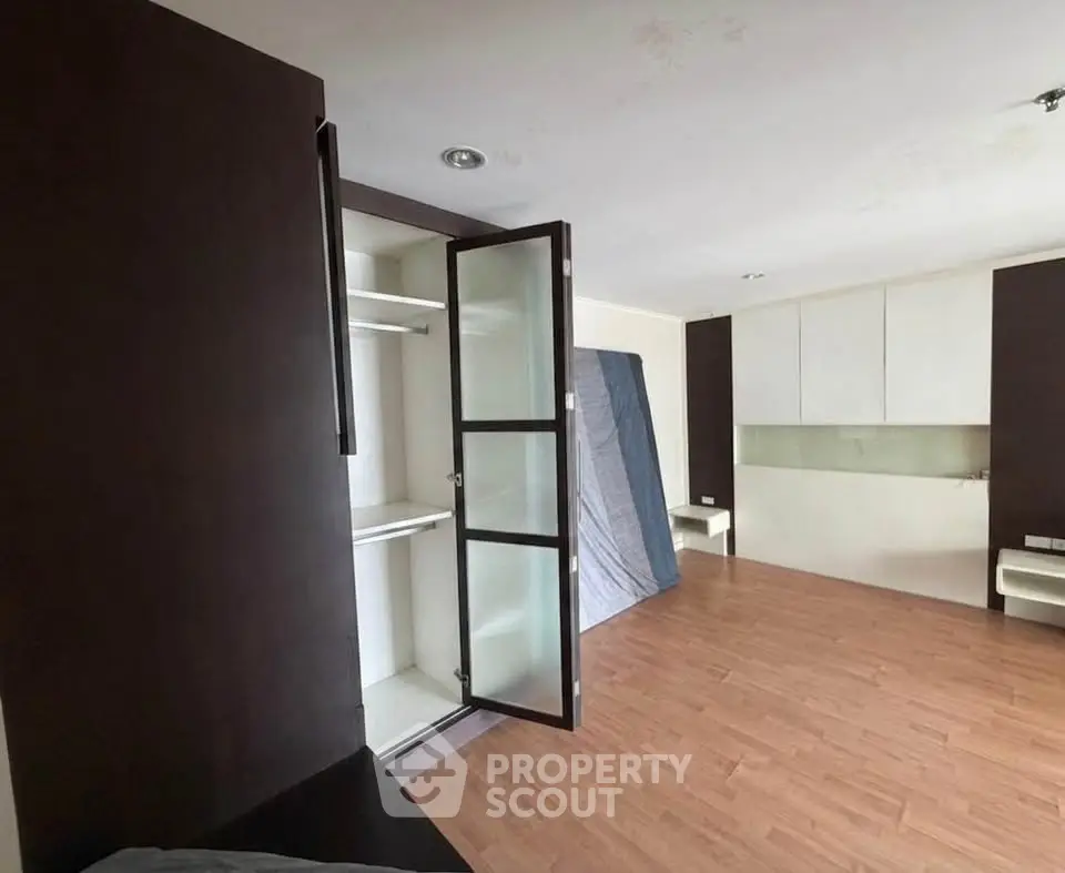 Spacious room with wooden flooring and built-in storage cabinets