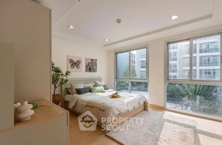 Spacious bedroom with large windows and modern decor in a luxury apartment.