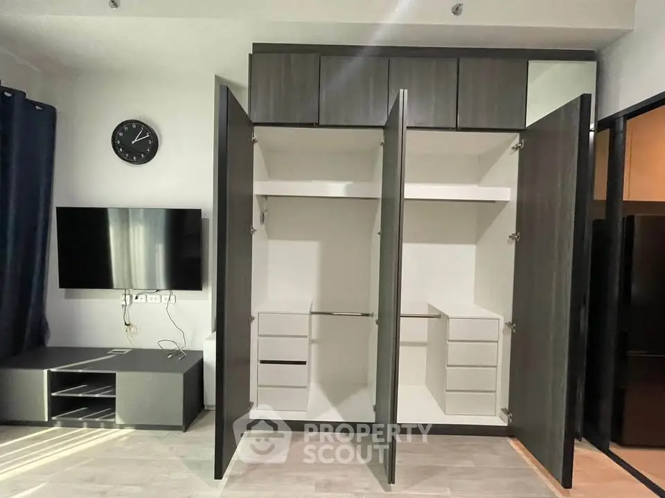 Spacious modern living room with open wardrobe and wall-mounted TV
