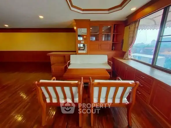 Spacious living room with wooden furniture and large window offering scenic views.