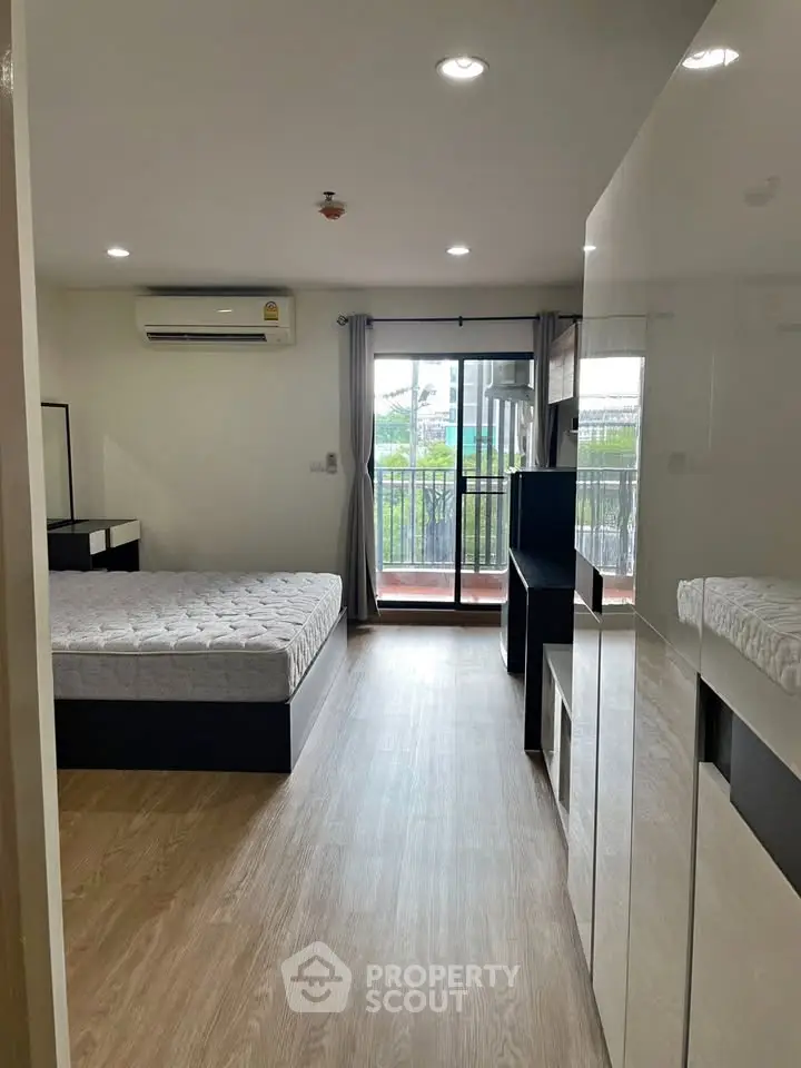 Spacious bedroom with balcony access and modern furnishings in a stylish apartment.