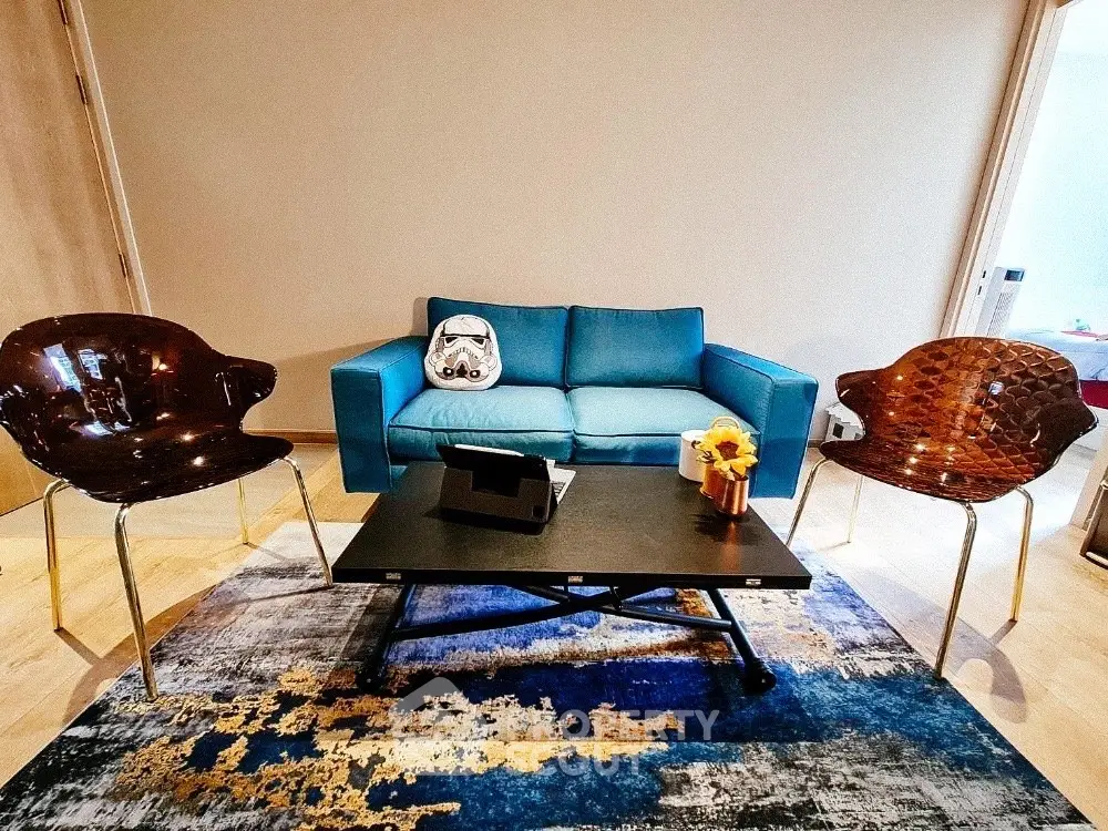 Stylish living room with modern blue sofa and chic chairs on a patterned rug.