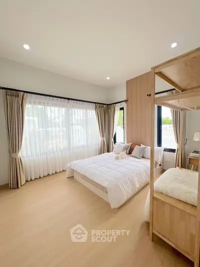 Spacious bedroom with modern decor and large windows for natural light.