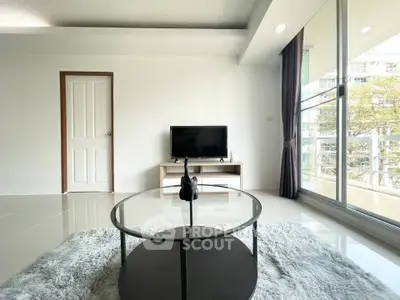 Modern living room with sleek decor and large windows offering natural light and a view.
