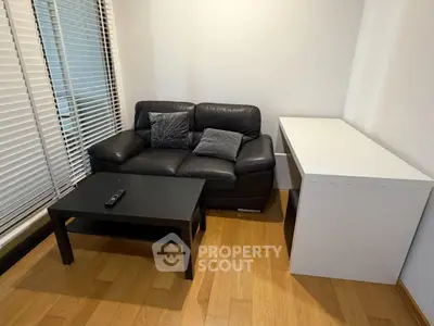 Cozy living room with black leather sofa and modern furniture, perfect for relaxation.