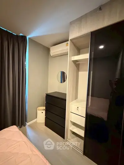 Modern bedroom with sleek black wardrobe and air conditioning unit, perfect for comfortable living.