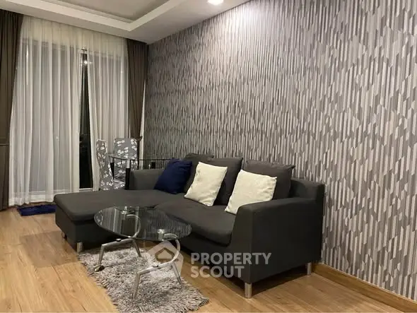 Stylish living room with modern gray sofa and chic wallpaper design.