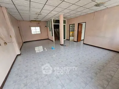 Spacious unfurnished living room with tiled flooring and ceiling lights, ready for customization.
