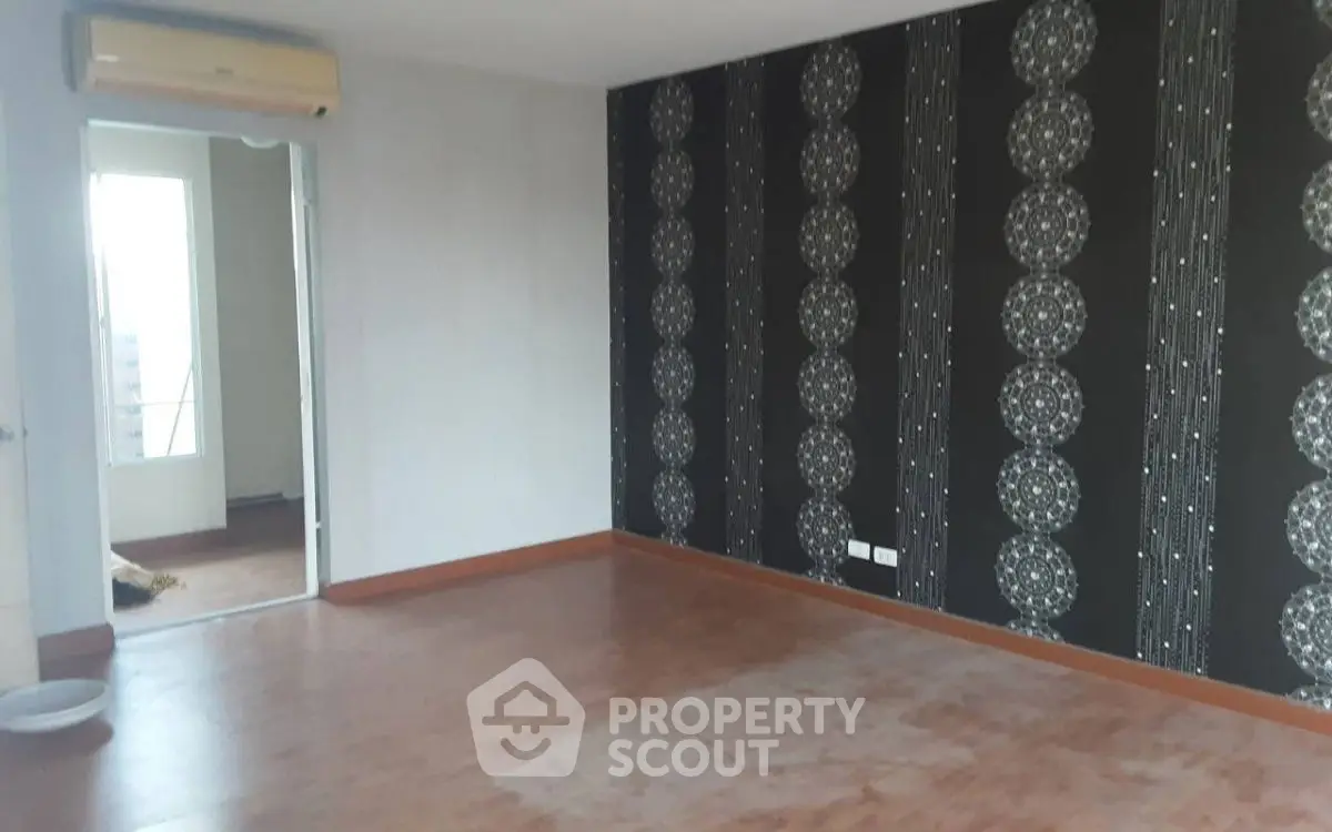 Spacious unfurnished room with decorative wallpaper and wooden flooring, ideal for customization.