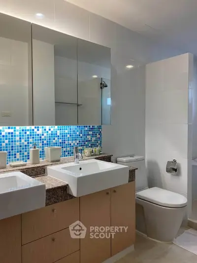 Modern bathroom with dual sinks and mosaic tile backsplash in a stylish apartment.