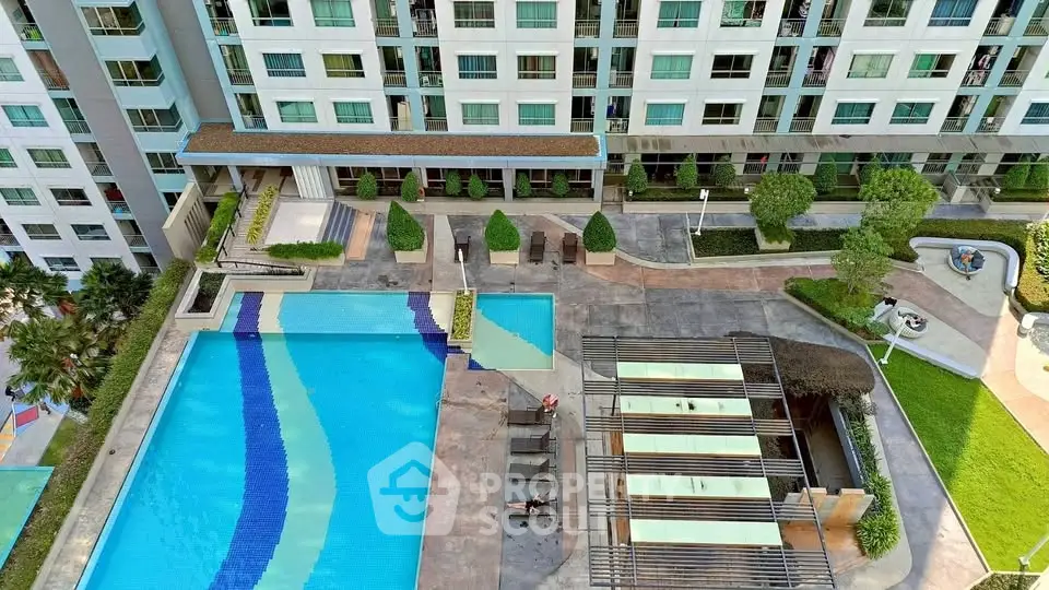 Stunning aerial view of modern apartment complex with large swimming pool and landscaped garden.