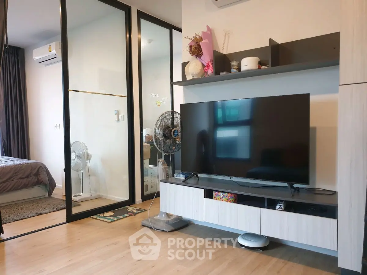 Modern living room with sleek TV unit and view into cozy bedroom