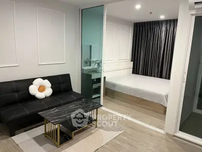 Modern studio apartment with stylish living area and cozy bedroom separated by glass partition.