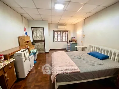 Cozy bedroom with wooden flooring and natural light, featuring a comfortable bed and air conditioning.