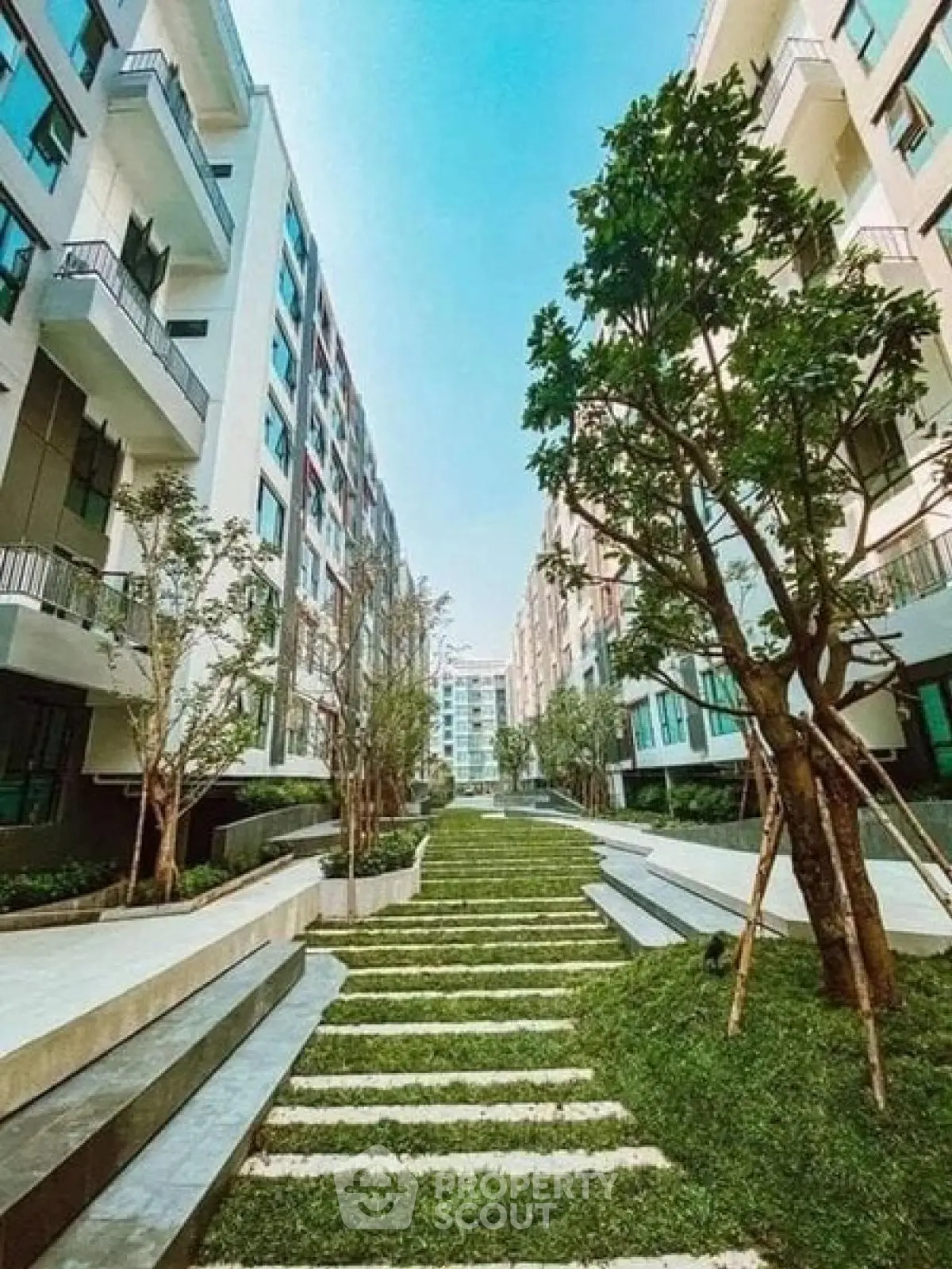 Modern apartment complex with lush green landscaping and contemporary architecture.
