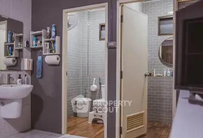 Modern bathroom with stylish gray tiles and wooden flooring, featuring a sleek sink and round mirror.