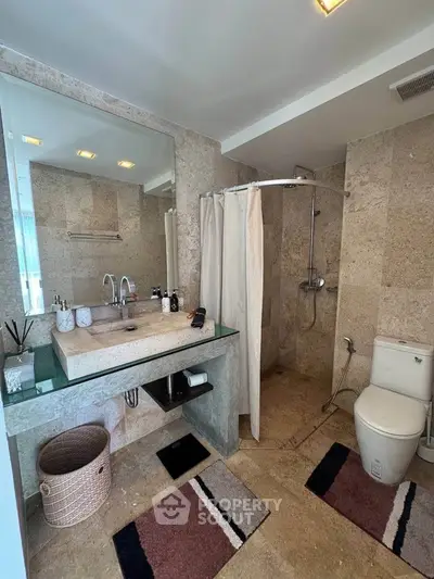 Luxurious bathroom with modern fixtures and elegant stone tiles, featuring a spacious shower and stylish vanity.