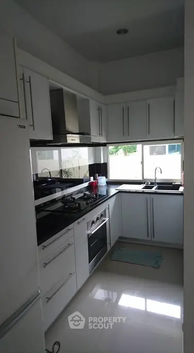 Modern kitchen with sleek white cabinets and gas stove in a cozy layout.