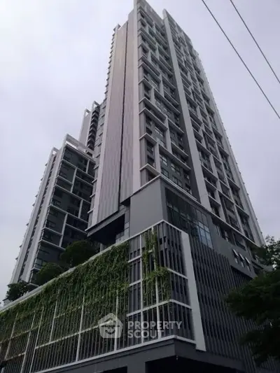 Modern high-rise building with sleek design and lush greenery facade