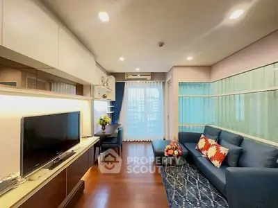 Modern living room with sleek design, featuring a cozy blue sofa, large TV, and elegant decor.