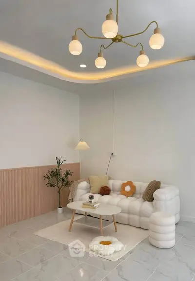 Stylish modern living room with plush white sofa, elegant lighting, and chic decor accents.