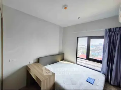Cozy bedroom with city view, featuring a modern bed and desk, perfect for urban living.