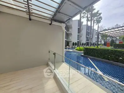 Modern apartment balcony with pool view and lush greenery, perfect for relaxation and leisure.