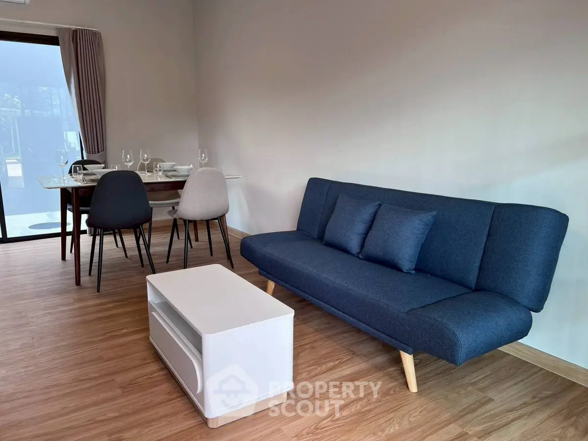 Modern living room with stylish blue sofa and elegant dining area, perfect for cozy gatherings.