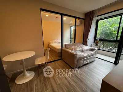 Modern studio apartment with cozy bedroom and living area, featuring large windows and stylish furnishings.