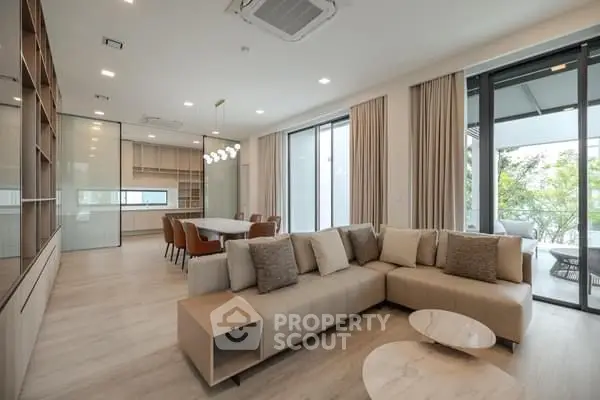 Spacious modern living room with open layout and elegant furnishings, featuring large windows and natural light.