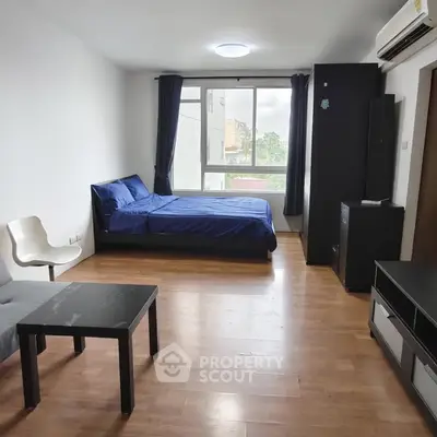 Spacious studio apartment with modern furnishings and large window view.