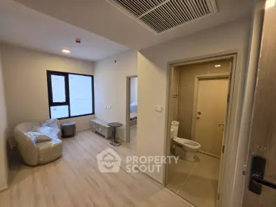 Modern apartment interior with cozy living area and adjacent bathroom, featuring sleek design and natural light.
