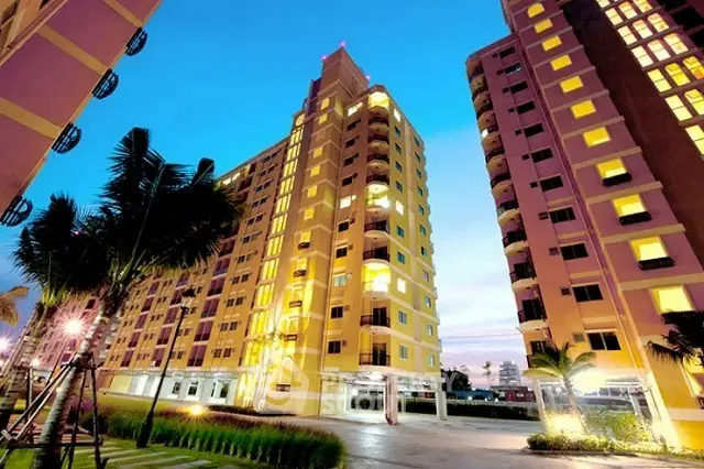 Stunning evening view of a modern high-rise apartment building with illuminated windows and lush landscaping.