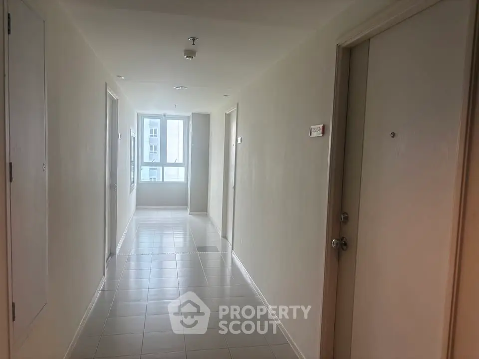 Bright apartment corridor with tiled flooring and natural light from window.