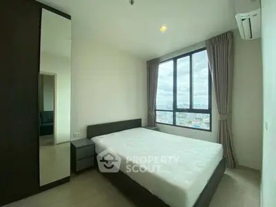 Modern bedroom with large window offering city view, featuring minimalist design and ample natural light.