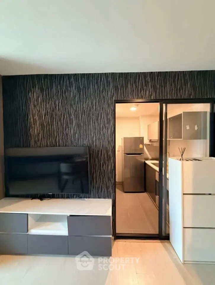 Modern living room with sleek TV unit and view into contemporary kitchen