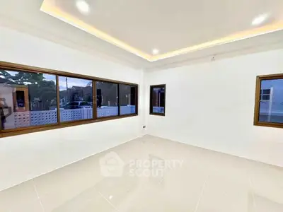 Spacious empty room with large windows and modern lighting