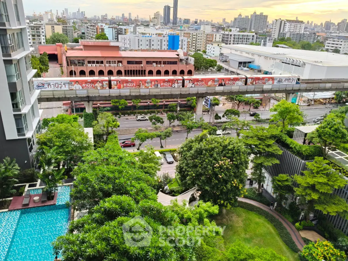 Aerial view of urban residential area with lush gardens and swimming pool, city skyline in background.